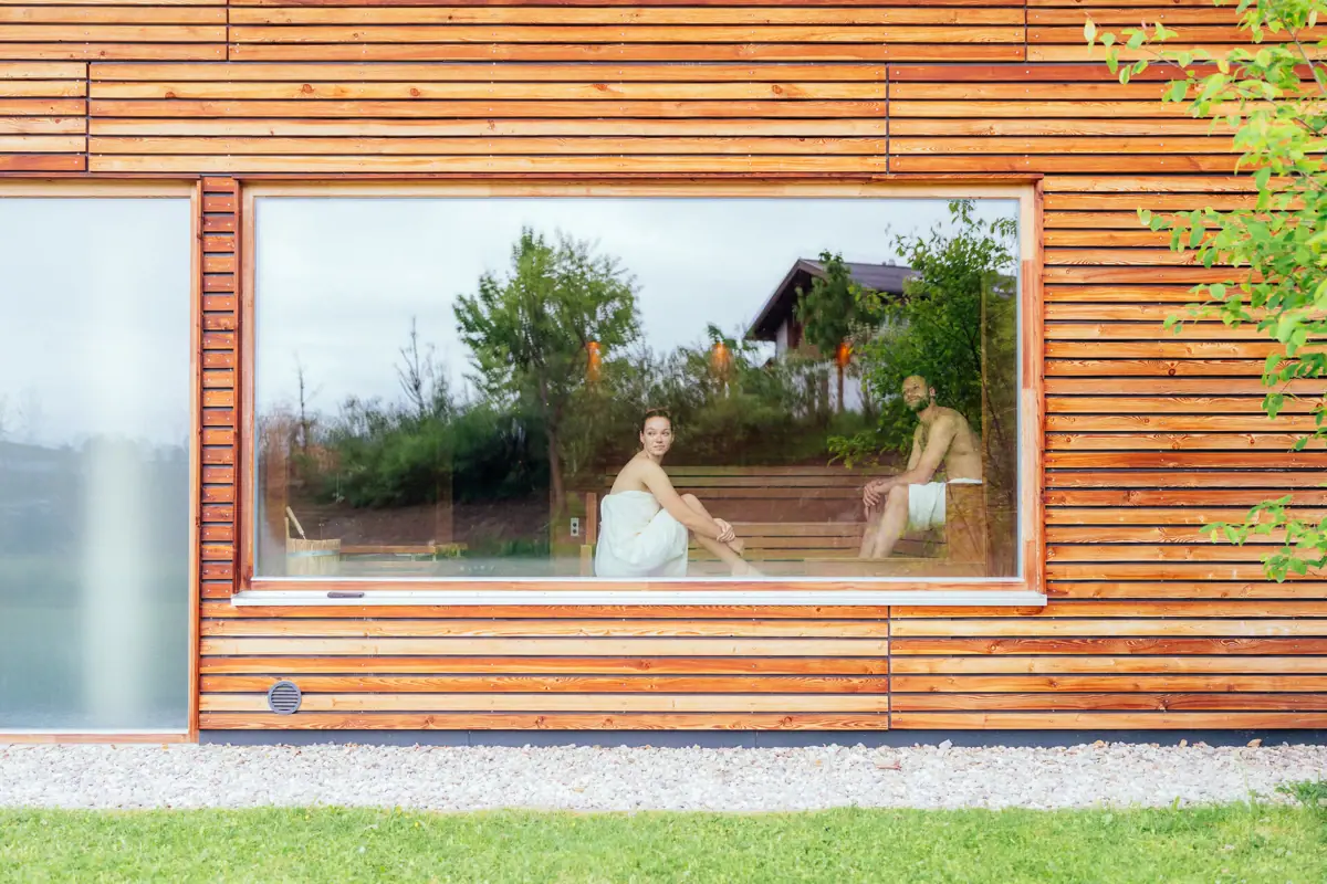 Sauna Ein Mann und eine Frau sitzen auf einer Bank in einem Holzhaus.