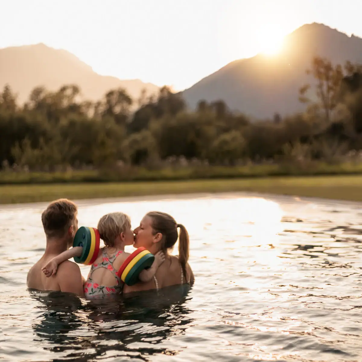 Familienurlaub Eine Gruppe von Menschen im Pool, ein Kind gibt einen Kuss.