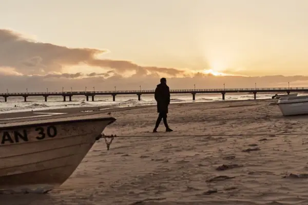 Eine Person geht am Strand entlang.