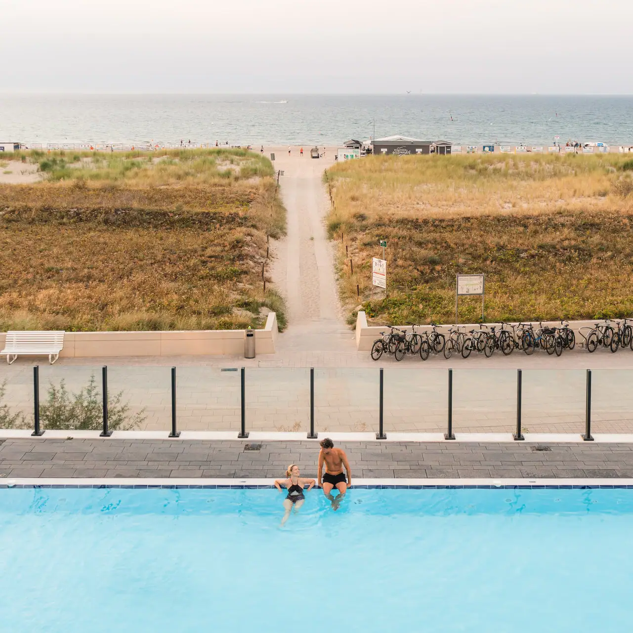 Wellness im aja Warnemünde Ein Mann und eine Frau im Pool mit Blick auf den Strand.