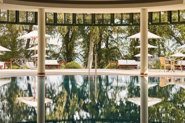 Ein Pool mit Sonnenschirmen und Stühlen im Hintergrund.