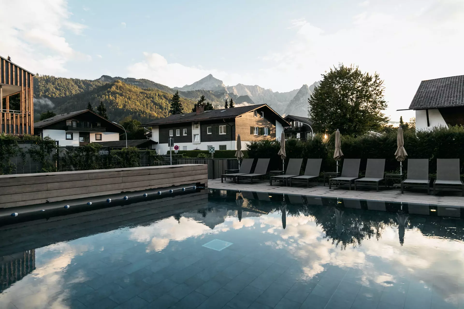 Pool umgeben von Liegestühlen mit einem Gebäude und Bergen im Hintergrund