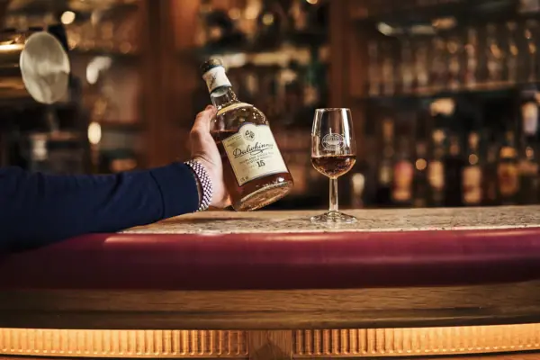 Whiskey Eine Hand hält eine Flasche Alkohol neben einem Weinglas.