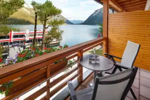 Doppelzimmer Balkon Ein Balkon mit Tisch und Stühlen mit Blick auf einen See.