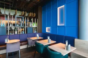 Bar Blaue Sitzbank mit Tischen und Stühlen in einem Innenraum.