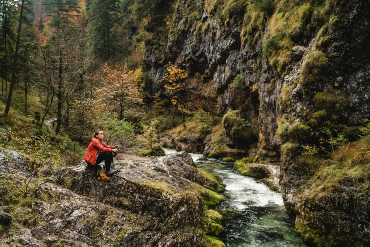 Eine Frau sitzt auf einem Felsen am Fluss.