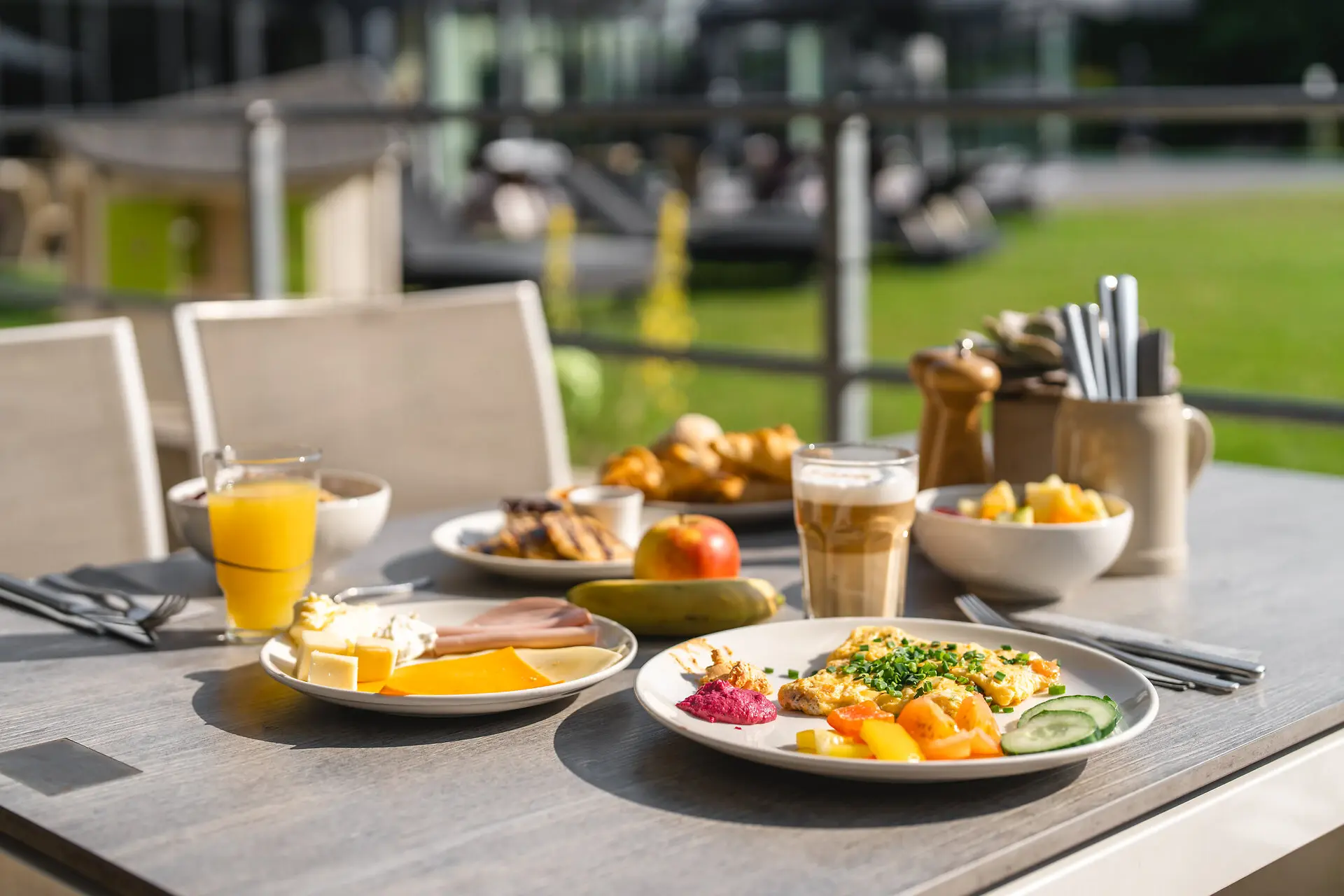 Auf einer Außenterrasse steht ein gedeckter Frühstückstisch in der Morgensonne. 