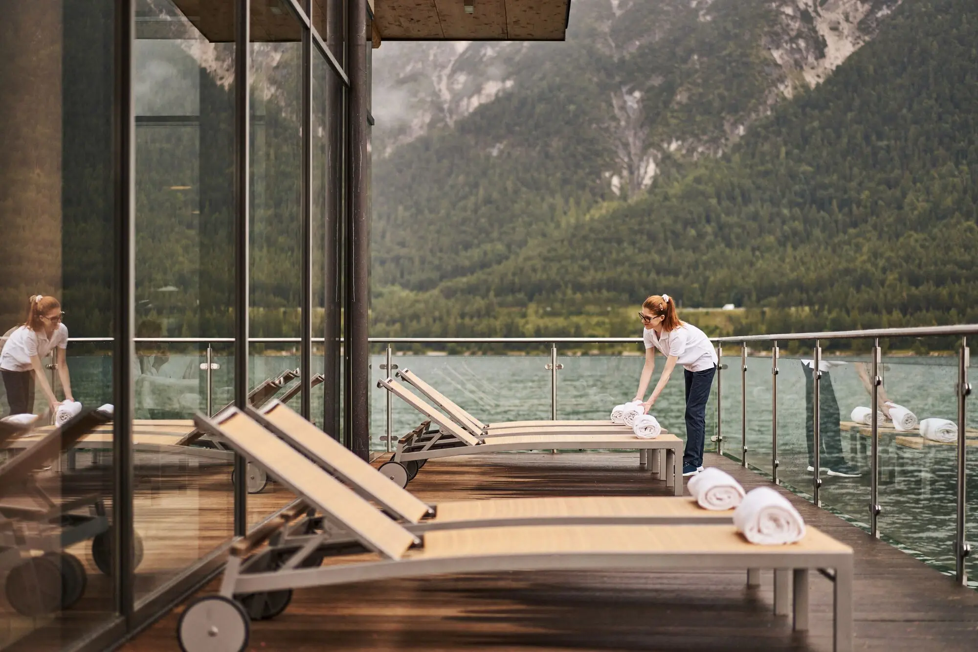 Frau legt Handtücher auf Liegen auf einer Terrasse direkt am Achensee.