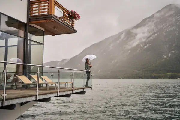 Eine Person steht auf einem Steg mit einem Regenschirm.
