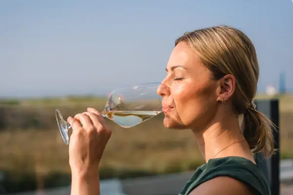 Eine Frau trinkt aus einem Weinglas.