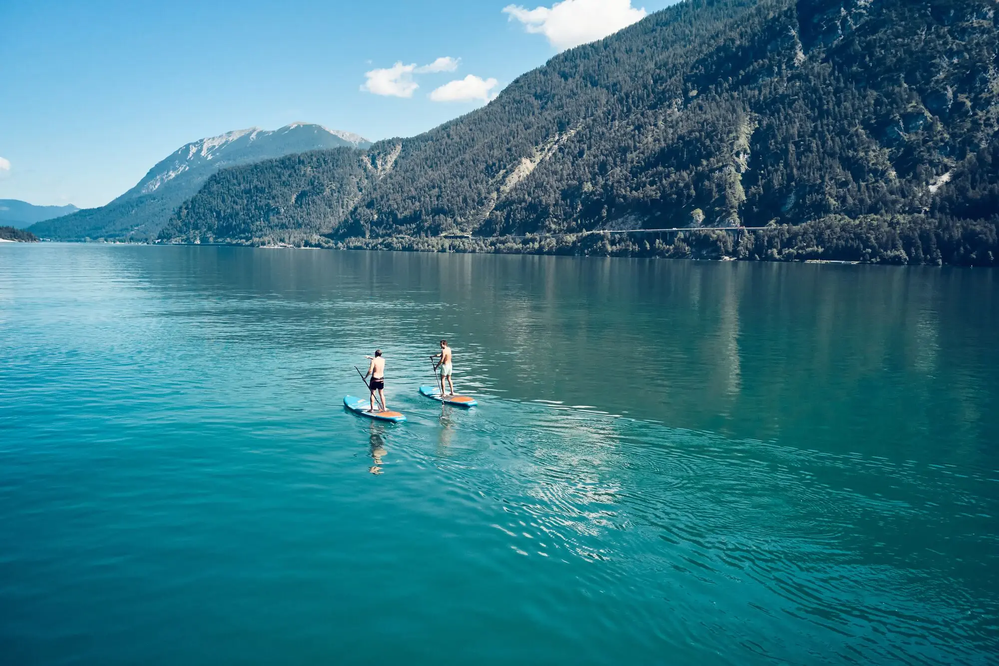 SUP auf dem Achensee Zwei Personen auf Paddleboards auf einem See.