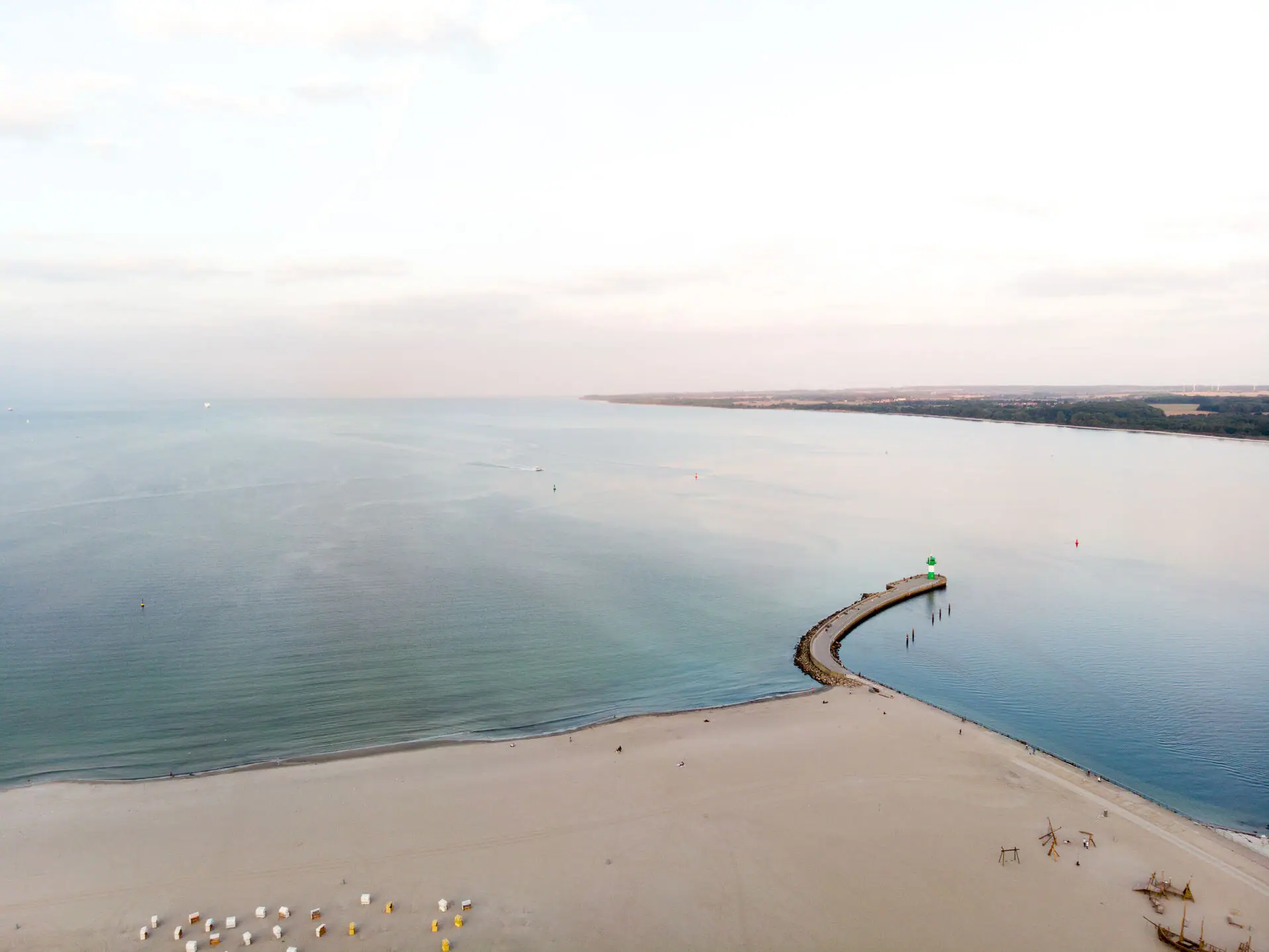 Ein Strand mit einem Pier und Menschen darauf.