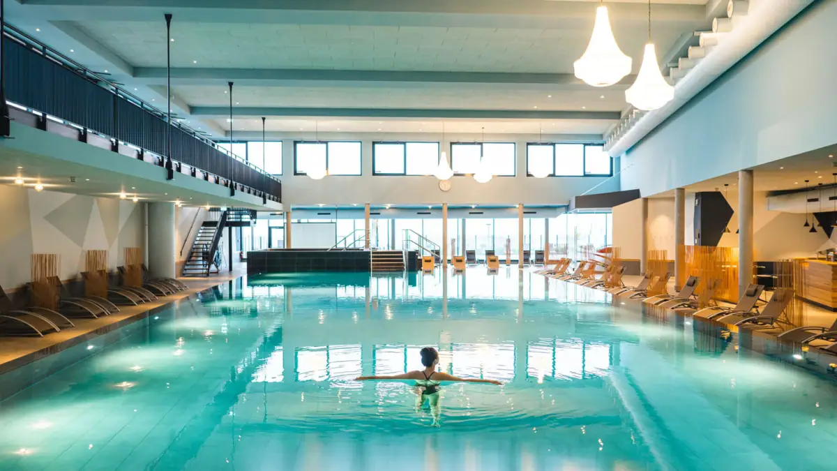 Innenpool aja Travemünde  Eine Frau in einem Schwimmbecken.