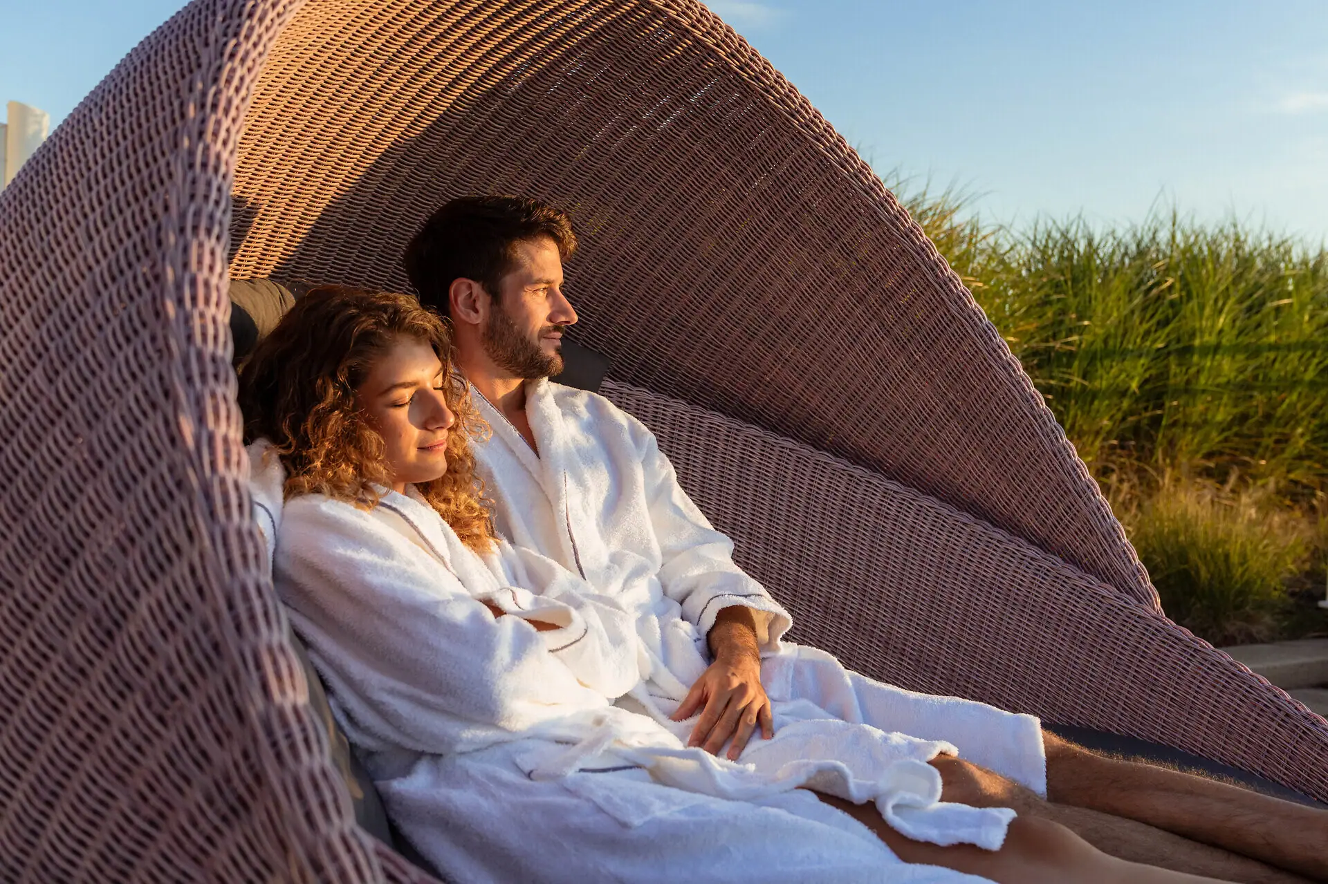Ruhebereich Ein Mann und eine Frau in Bademänteln sitzen in einem Korbstuhl.