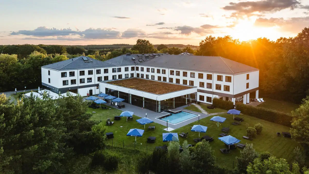 Ein Gebäude mit einem Pool und Sonnenschirmen in der Mitte.