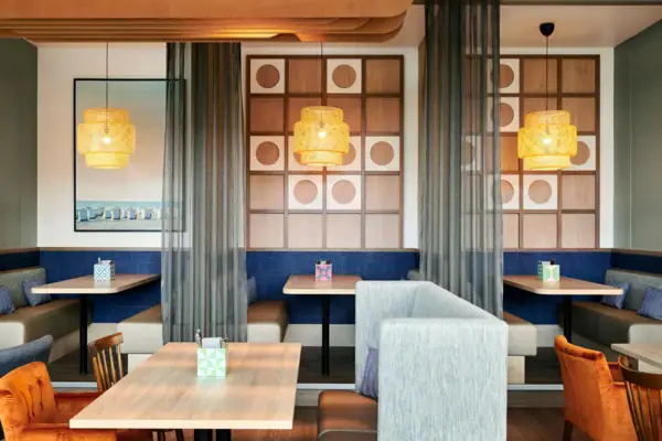 Ein Raum mit Tischen und Stühlen und einzelnen Kojen, abgetrennten Bereichen.