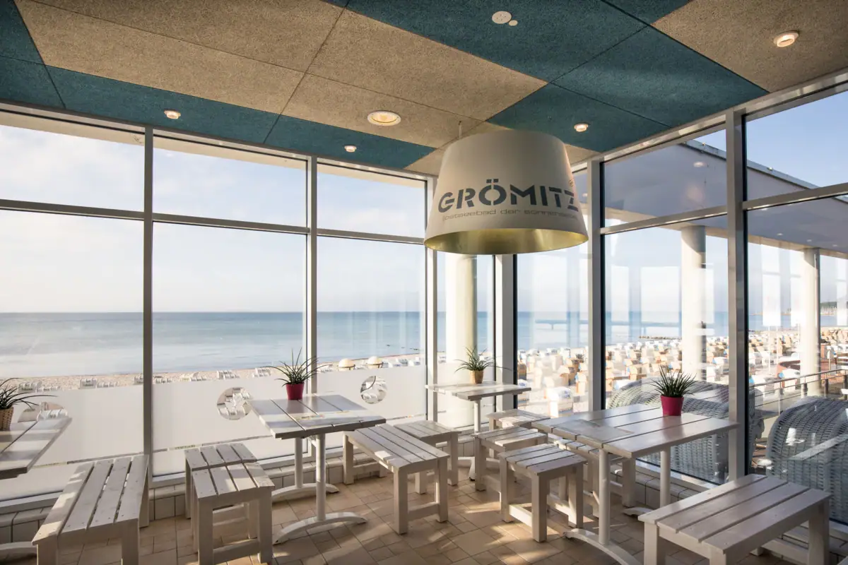 Ein Raum mit Tischen, Stühlen und einem großen Fenster.