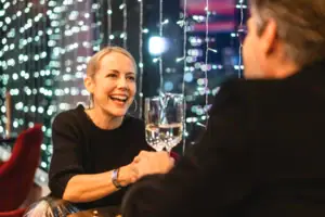 Sekt anstoßen Eine Frau hält ein Weinglas, daneben ein Mann im schwarzen Hemd.