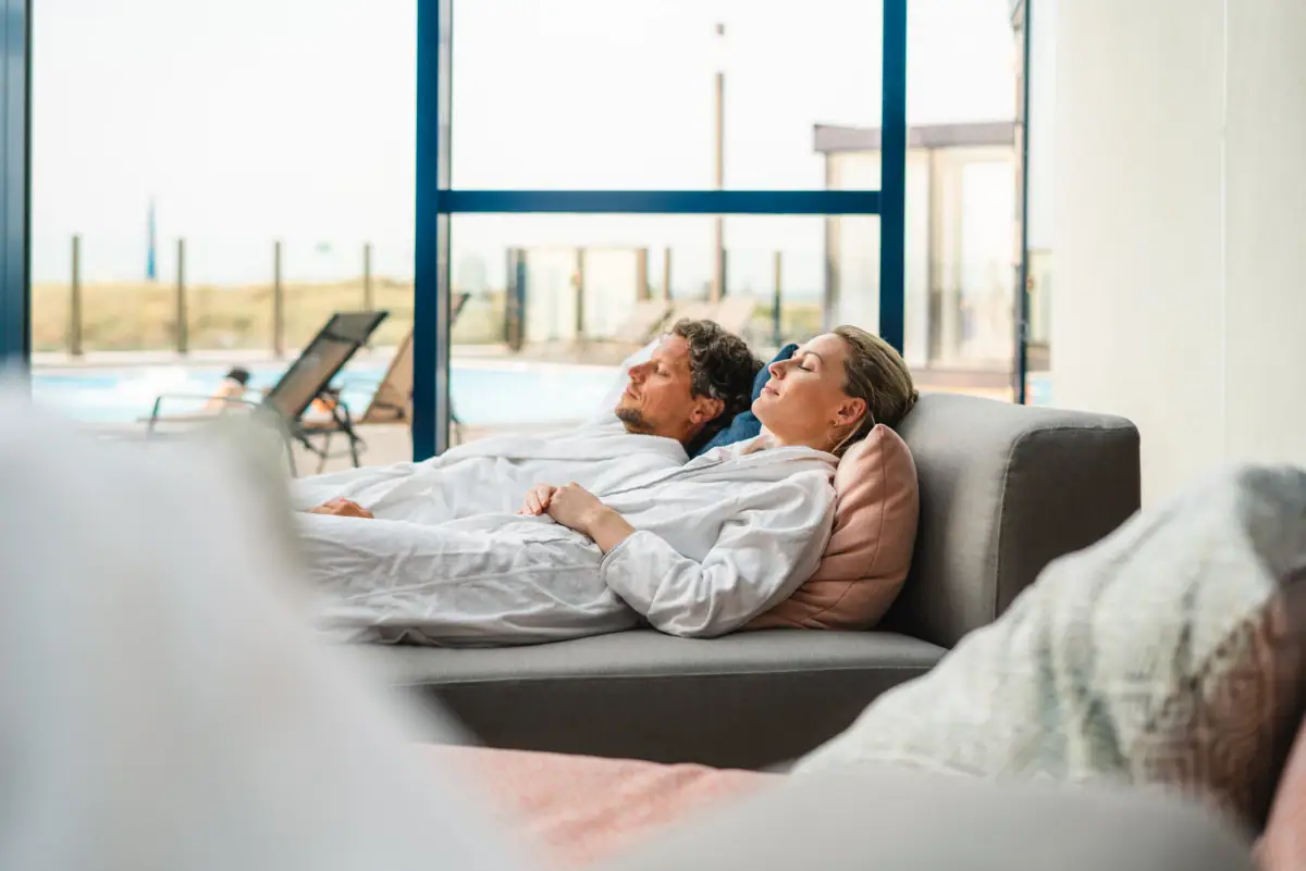 Wellnessbereich im aja Warnemünde Ein Mann und eine Frau liegen auf einem Sofa.