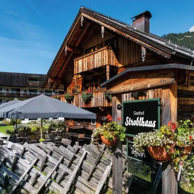 Eine urige Holzhütte mit einem Schild und Sonnenschirmen.