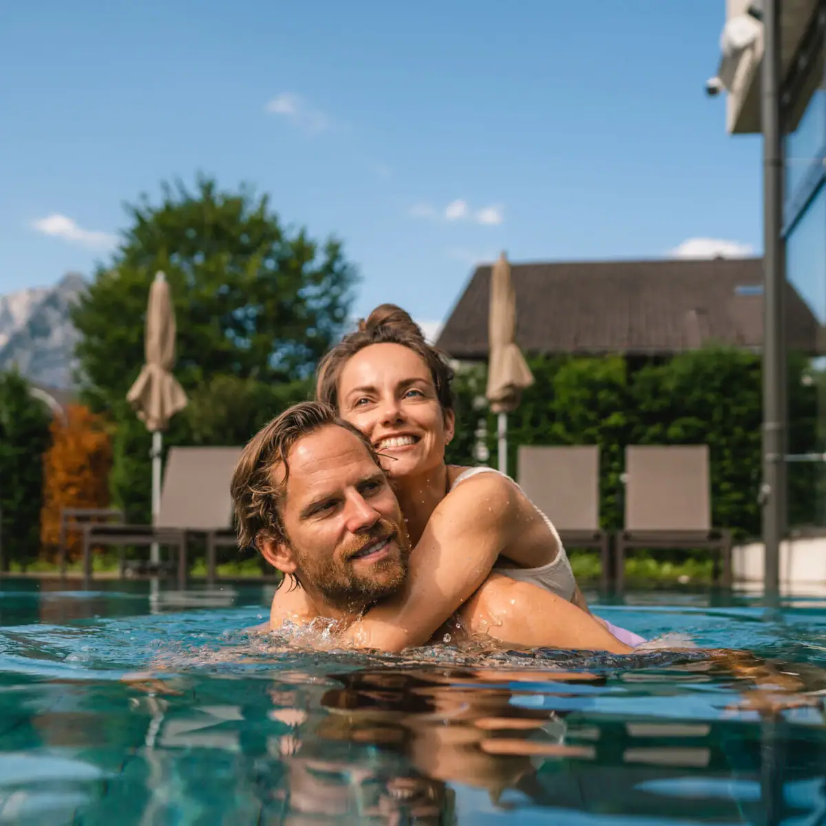Ein Mann und eine Frau im Pool, beide lächelnd.