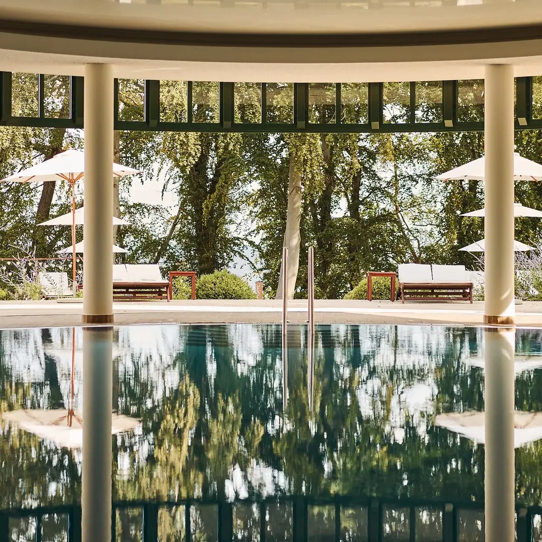 Innenpool aja Nordperd & Villen Ein Pool mit Sonnenschirmen und Stühlen im Hintergrund.