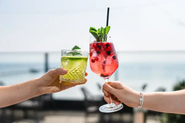 Ein Paar Hände hält Cocktails mit Erdbeergarnitur.