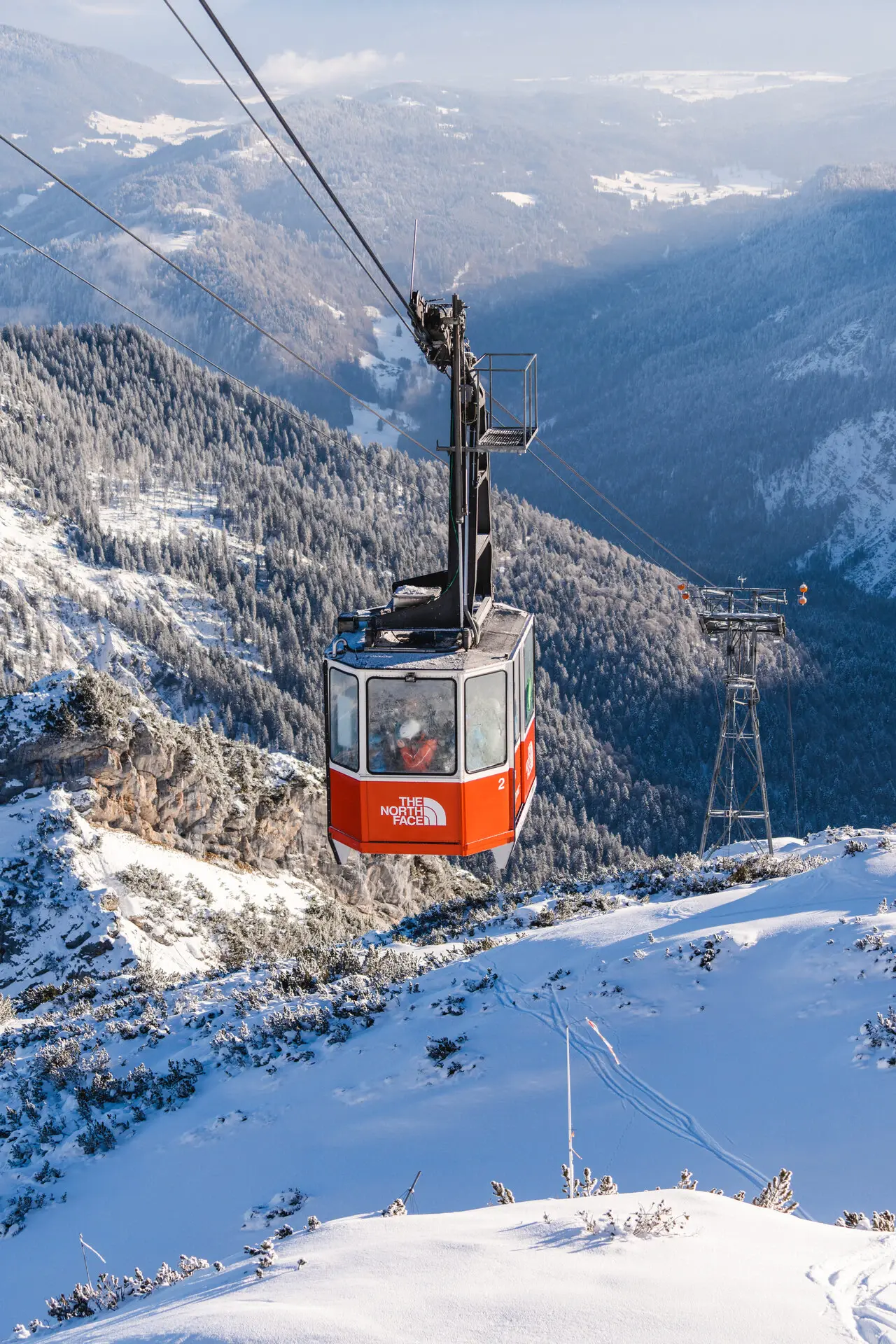 Rote Seilbahn auf einem verschneiten Berg.