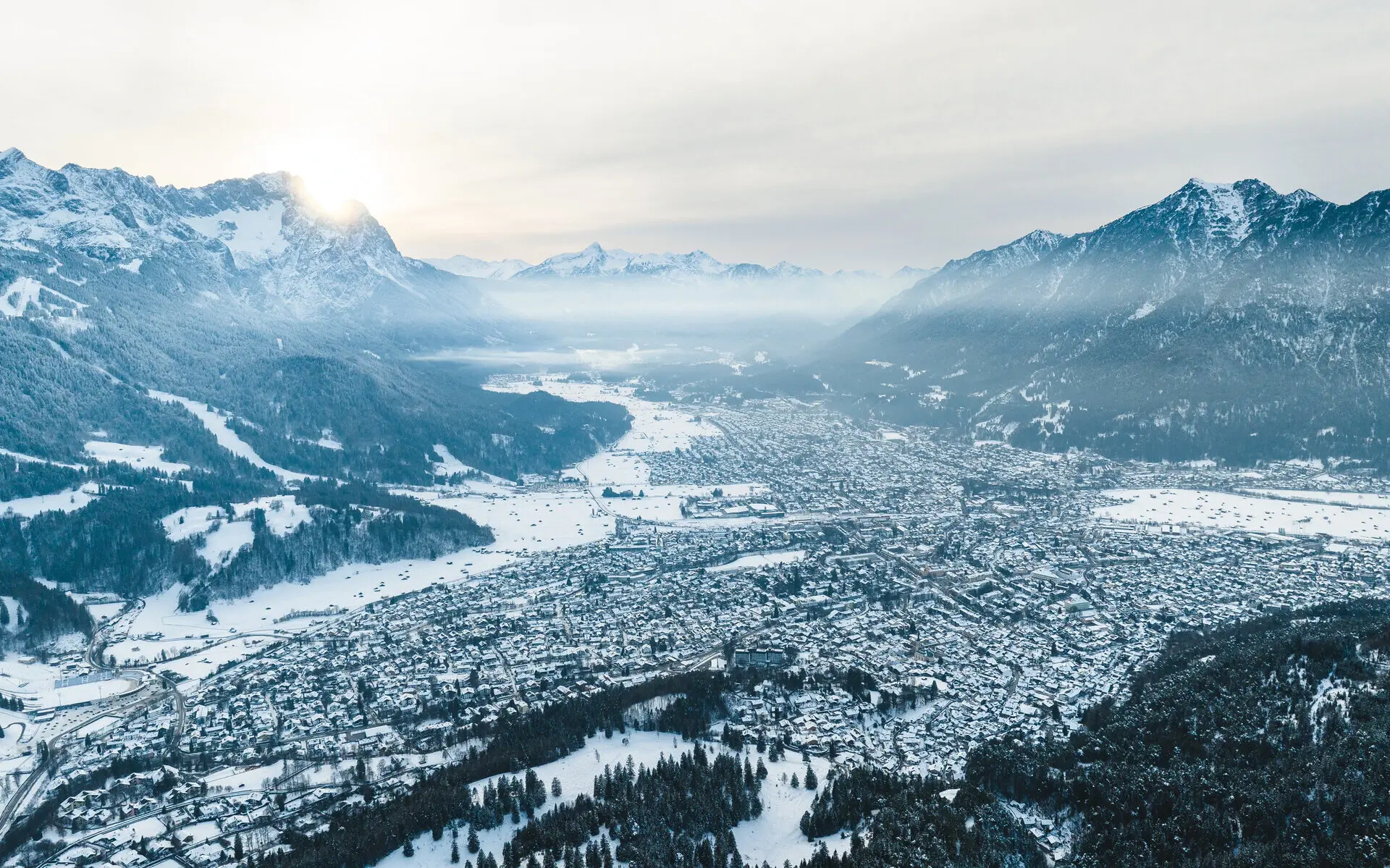 Schneebedeckte Stadt mit Berglandschaft im Hintergrund.