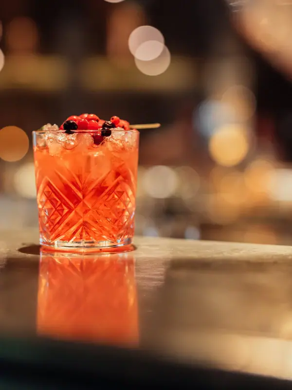Ein Glas mit einem Cocktail und Beeren als Garnitur.