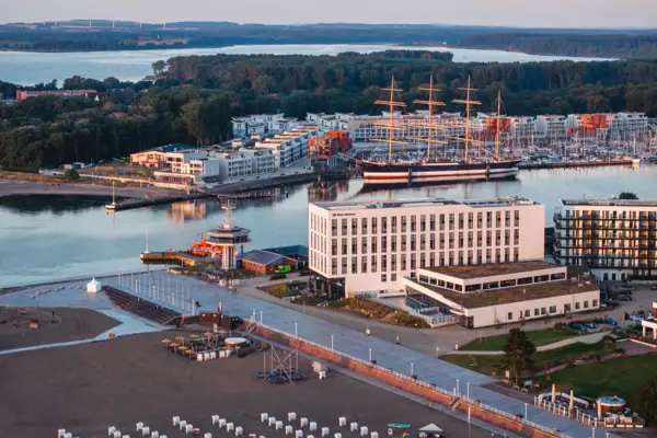 Drohnenaufnahme vom aja Hotel Travemünde mit dem Strand vor der Tür sowie dem Priwall und der Passat im Hintergrund.