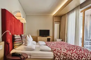 Bett mit einer rot-weißen Decke und einem Fernseher im Hintergrund.