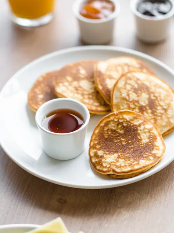 Pancakes Ein Teller mit Pfannkuchen und Saucen auf einem Tisch.