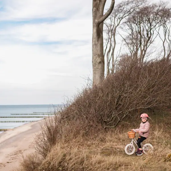 Küste Ein Kind auf einem Fahrrad auf einem Hügel am Strand.