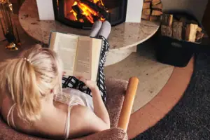 Lesen am Kamin Eine Frau liest ein Buch vor einem Kamin.