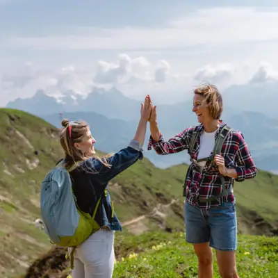 Teambuilding Zwei Frauen geben sich im Freien einen High Five.
