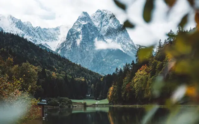 Ein See umgeben von Bäumen und Bergen.