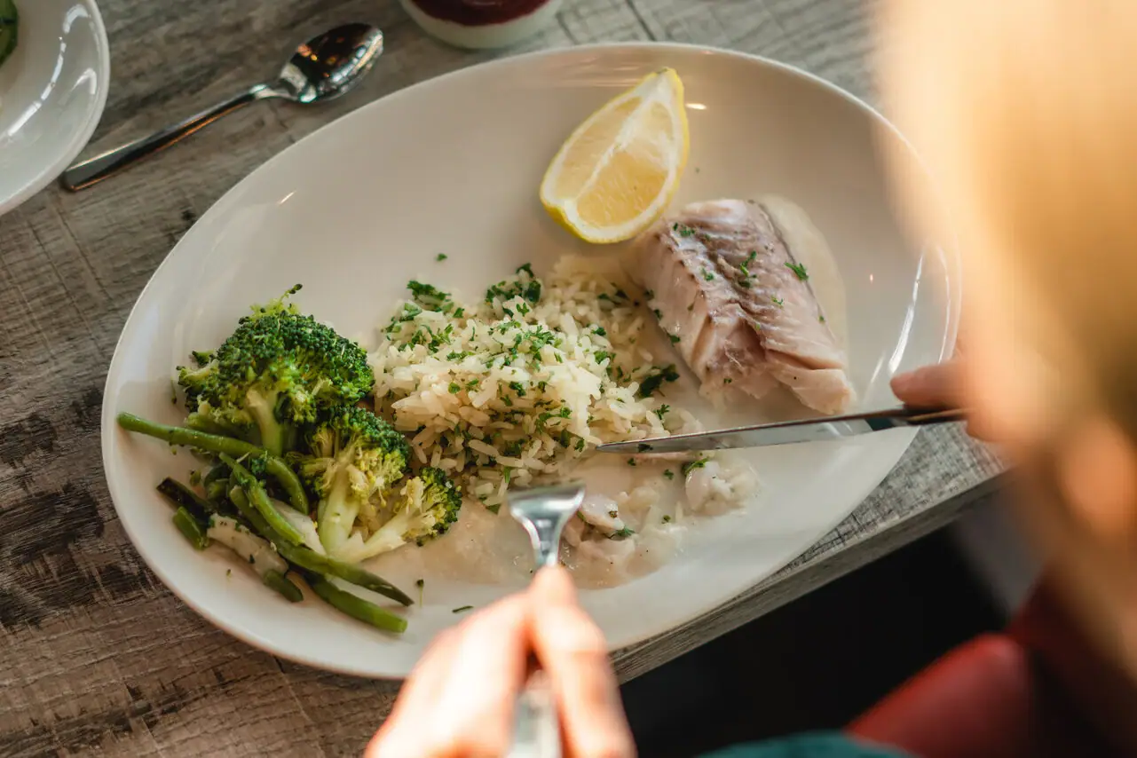 Fischgericht Person isst von einem Teller mit Essen.