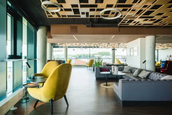 Bar mit Sitzgelegenheiten Ein Raum mit einem gelben Stuhl und Tischen.