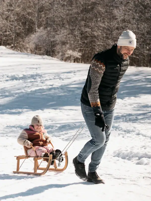 Ein Mann und ein Kind auf einem Schlitten im Schnee.