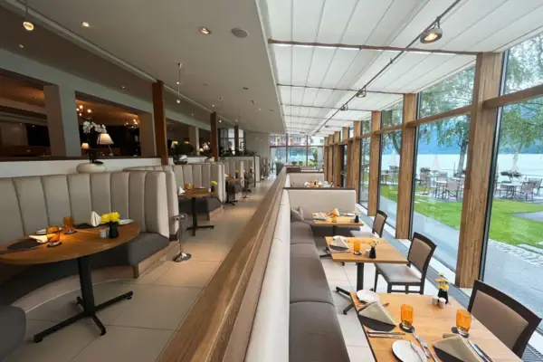 Innenansicht eines Restaurants mit Tischen und Stühlen.