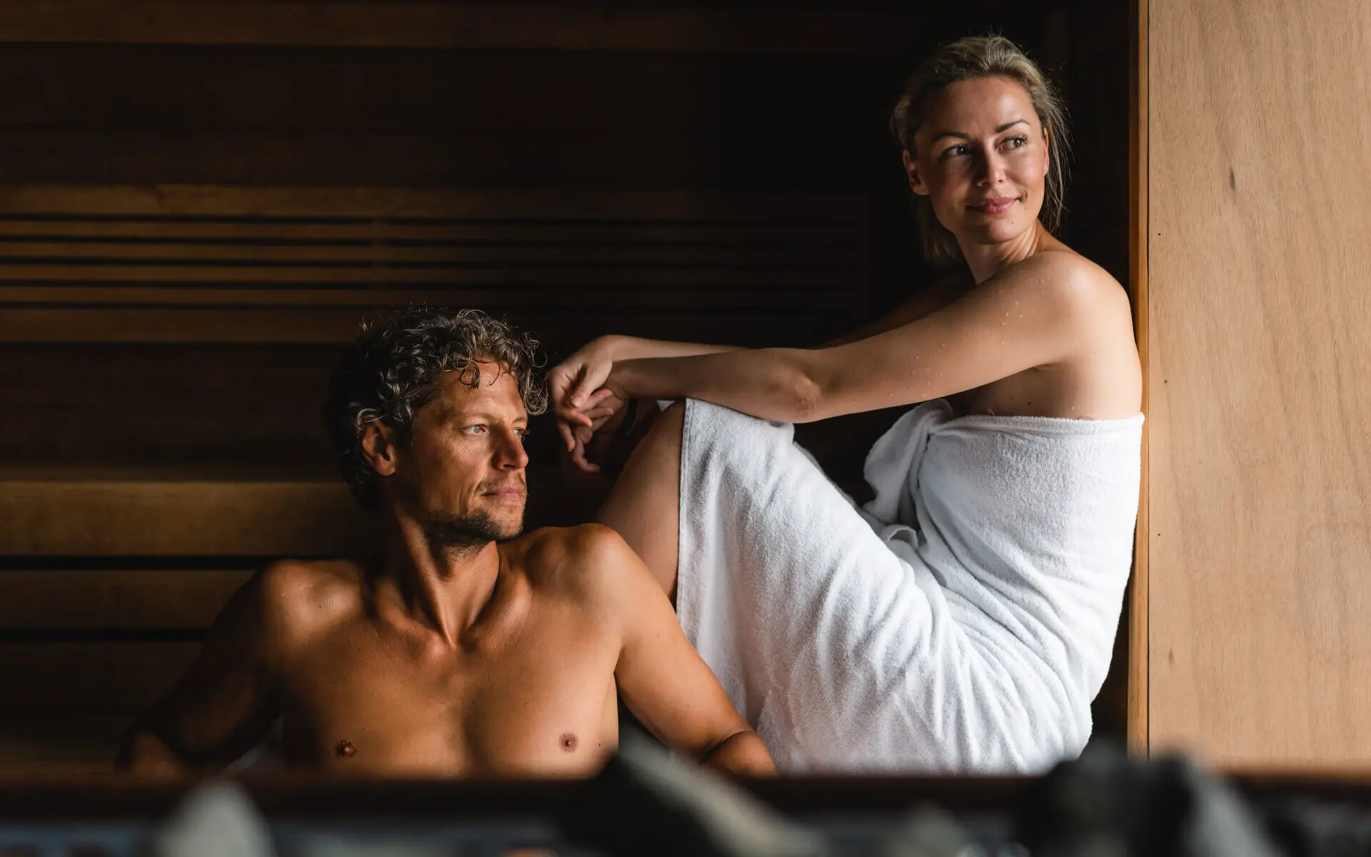 Eine Frau sitzt mit Mann in einer Sauna