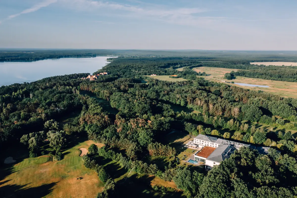 Ein großes Gebäude umgeben von Bäumen und einem Gewässer.