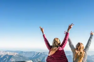 Aussicht Zugspitze Zwei Frauen mit erhobenen Armen, die in den Himmel schauen.