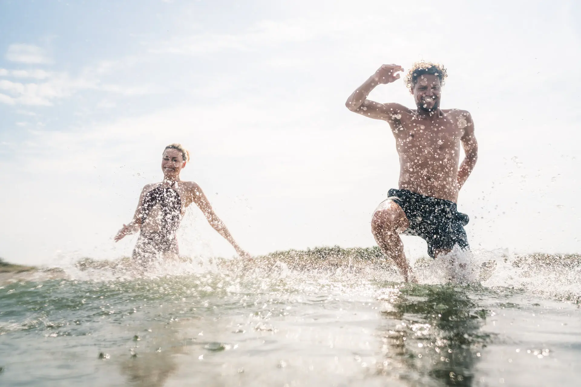 Zwei Personen laufen im Wasser am Strand.