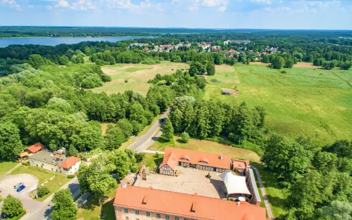 Haus mit rotem Dach unter blauem Himmel und umgeben von Bäumen.