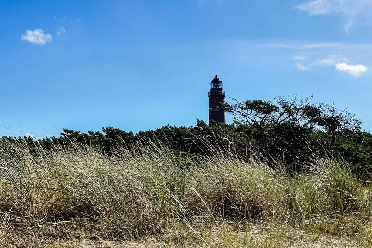 Ein Leuchtturm auf einem Grasfeld unter bewölktem Himmel.