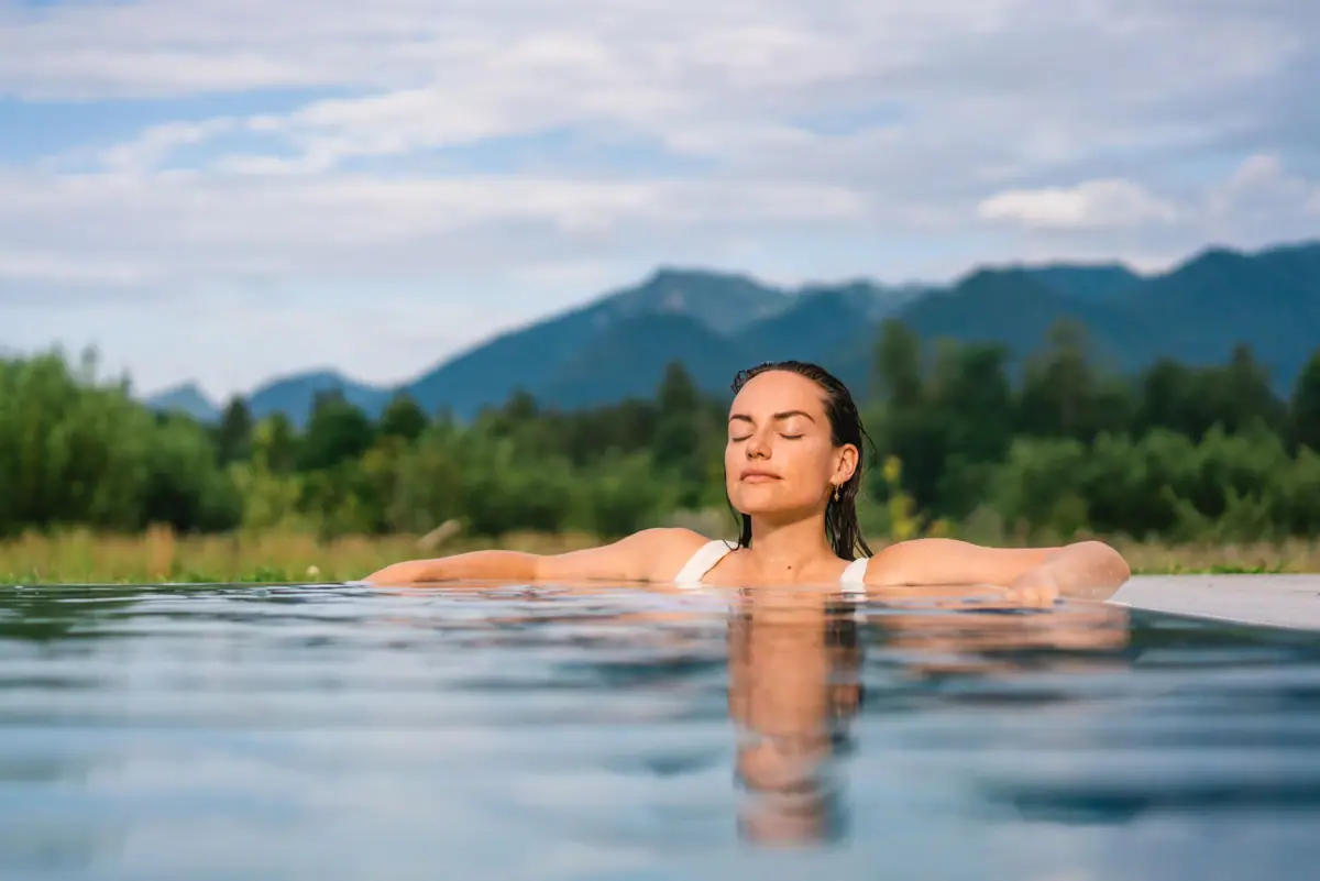 Eine Frau mit geschlossenen Augen im Pool in einem Wellnesshotel in Bayern.