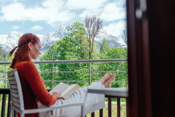 Zimmer mit Balkon Eine Frau sitzt auf einem Balkon und liest ein Buch.