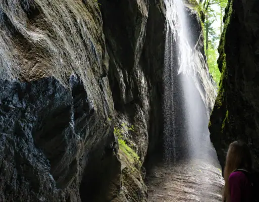 Eine Frau steht in einer Höhle mit einem Wasserfall.